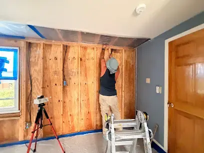 Technician working on opened wall framing with drying lights in Canoga Park